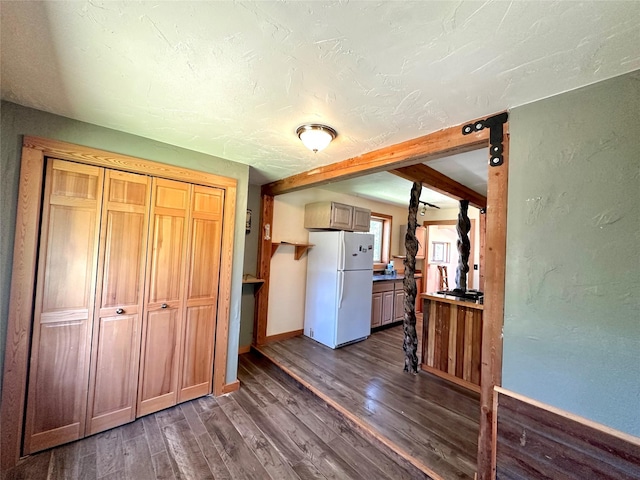 kitchen with baseboards, dark wood-style flooring, beam ceiling, and freestanding refrigerator