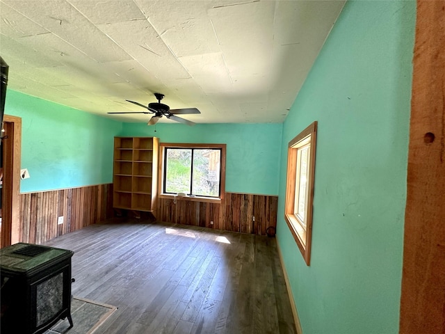 interior space featuring a wood stove, a wainscoted wall, and wood walls