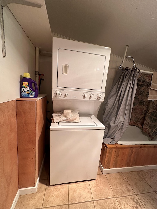 clothes washing area with stacked washer / dryer, laundry area, and light tile patterned flooring