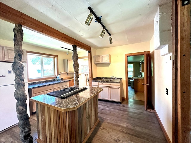 kitchen featuring a center island, dark countertops, black stovetop, dark wood-style floors, and freestanding refrigerator