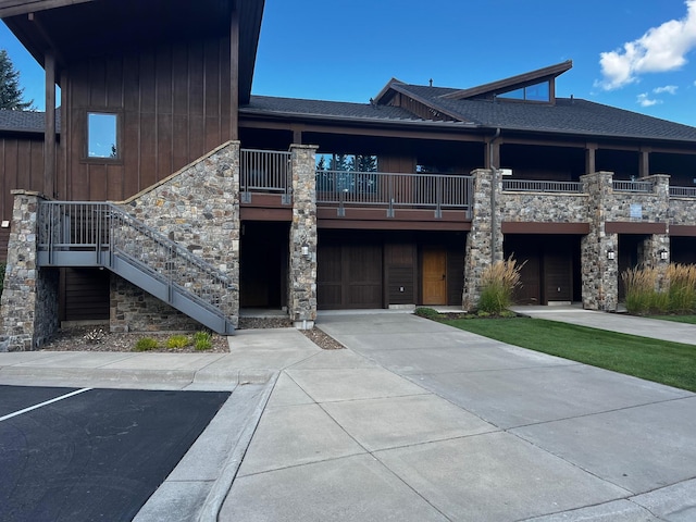 105 Oliver Ln Unit 7, Bigfork, MT 59911 - view of front facade featuring stone siding, a shingled roof, and a balcony
