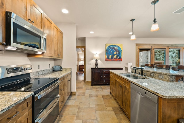 105 Oliver Ln Unit 7, Bigfork, MT 59911 - kitchen with appliances with stainless steel finishes, stone finish flooring, hanging light fixtures, light stone countertops, and recessed lighting