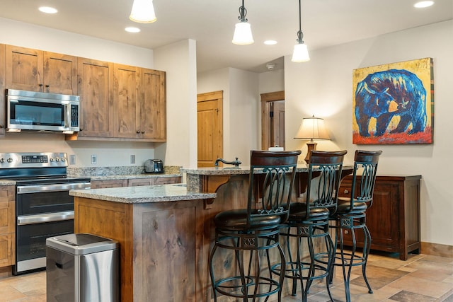 105 Oliver Ln Unit 7, Bigfork, MT 59911 - kitchen featuring appliances with stainless steel finishes, light stone finish floors, a breakfast bar, recessed lighting, and light stone countertops