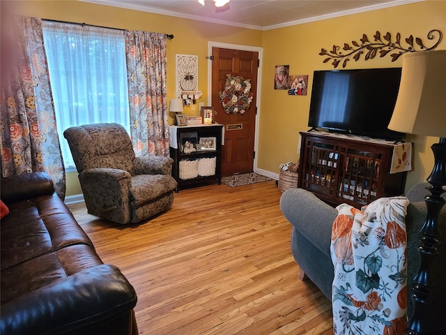 living area featuring wood-type flooring, a wealth of natural light, crown molding, and a ceiling fan