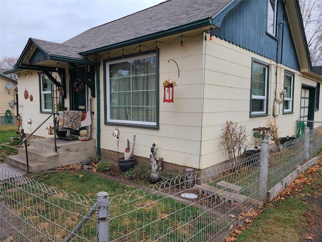 view of front of house with fence, a vegetable garden, and roof with shingles