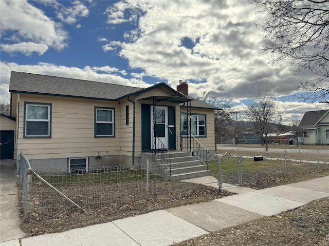 bungalow-style house with a chimney, roof with shingles, and a fenced front yard