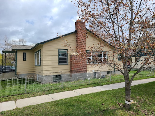 view of side of home with fence private yard, a lawn, and a chimney
