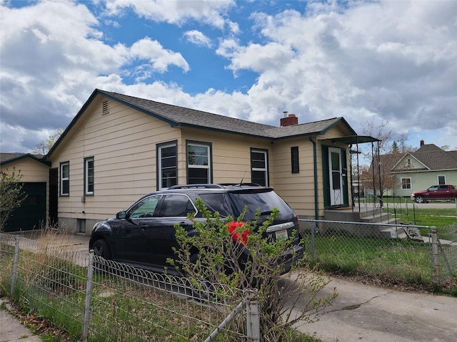 bungalow featuring fence private yard, a chimney, and roof with shingles