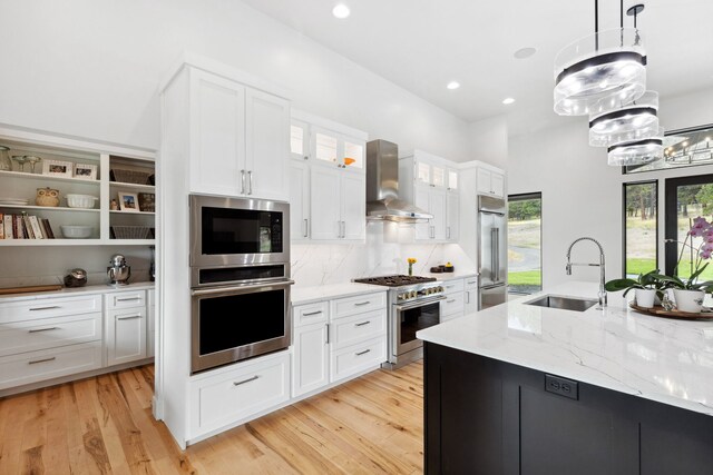 5608 Trinity Way, Florence, MT 59833 - kitchen featuring wall chimney range hood, a sink, built in appliances, white cabinets, and a notable chandelier