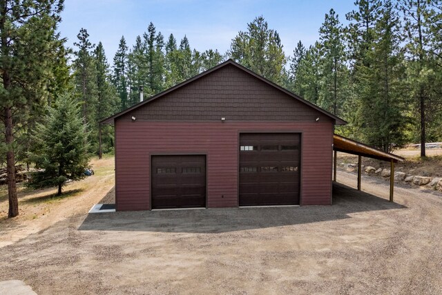 5608 Trinity Way, Florence, MT 59833 - garage featuring a forest view, a detached garage, and dirt driveway