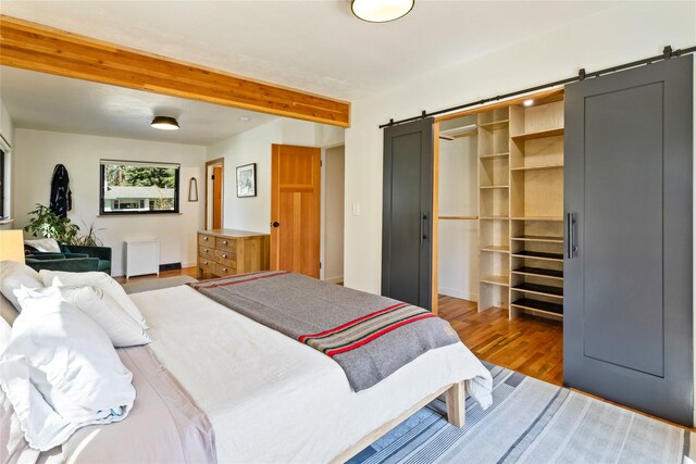 4210 Lincoln Rd, Missoula, MT 59802 - bedroom with a barn door, baseboards, a walk in closet, wood finished floors, and beam ceiling