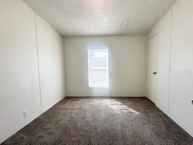 carpeted empty room with a textured ceiling