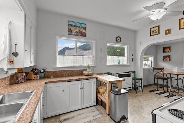 360 White House Ln, Bonner, MT 59823 - kitchen with ceiling fan, a sink, arched walkways, light countertops, and white cabinets