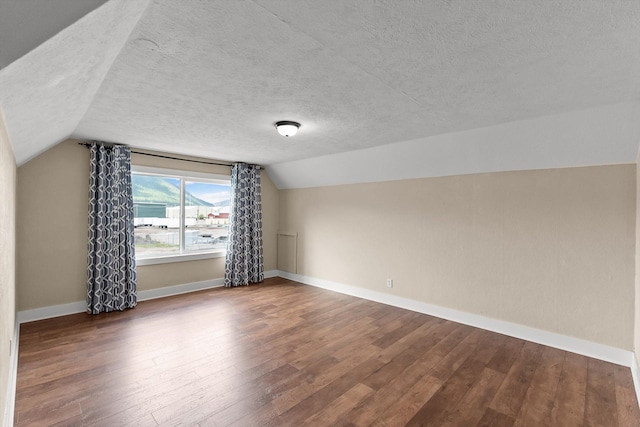 360 White House Ln, Bonner, MT 59823 - additional living space with a textured ceiling, vaulted ceiling, wood finished floors, and baseboards