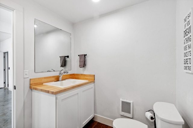 bathroom with baseboards, toilet, vanity, and heating unit