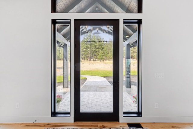 doorway to outside featuring wood finished floors, baseboards, and vaulted ceiling