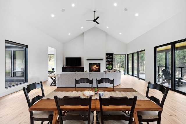 dining space with high vaulted ceiling, ceiling fan, a glass covered fireplace, and recessed lighting