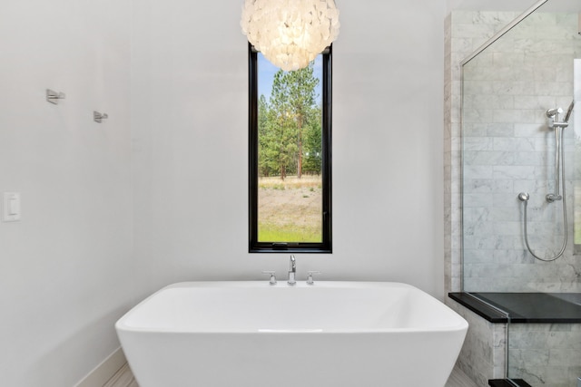 full bath with a shower stall, an inviting chandelier, a freestanding tub, and a sink