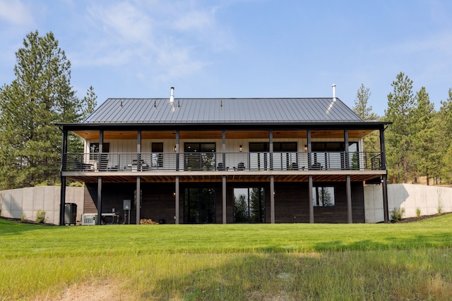 rear view of property featuring a standing seam roof, a yard, and metal roof