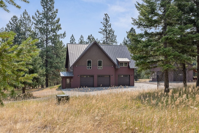 view of property exterior with a standing seam roof, driveway, metal roof, and a garage