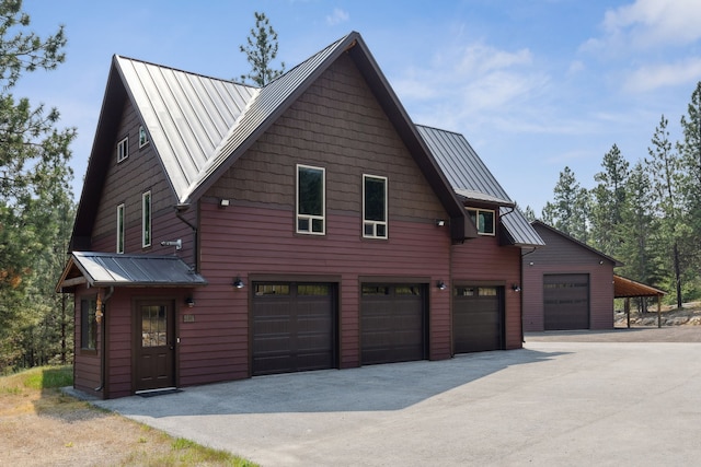 view of home's exterior with an attached garage, a standing seam roof, metal roof, and driveway