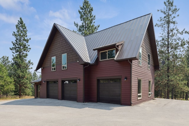 view of home's exterior featuring driveway, metal roof, and a garage