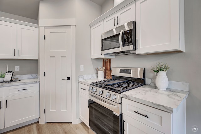 215 Meadow View Loop, East Helena, MT 59635 - kitchen featuring white cabinets, light wood-type flooring, light stone countertops, and stainless steel appliances