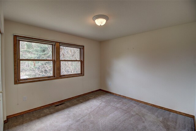 carpeted empty room featuring baseboards and visible vents