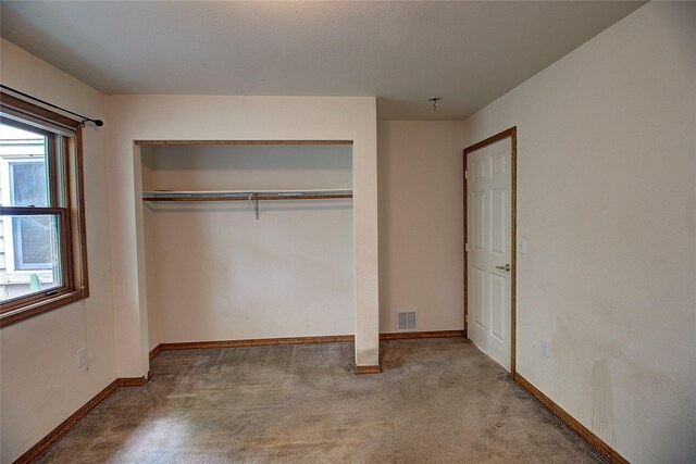 unfurnished bedroom with a closet, carpet floors, visible vents, and baseboards
