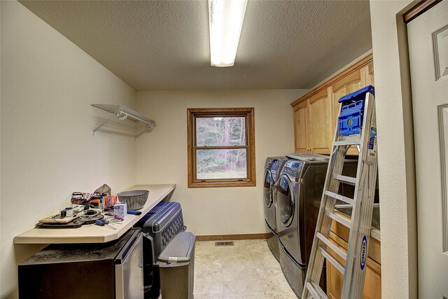 laundry area with washing machine and clothes dryer, cabinet space, a textured ceiling, and baseboards