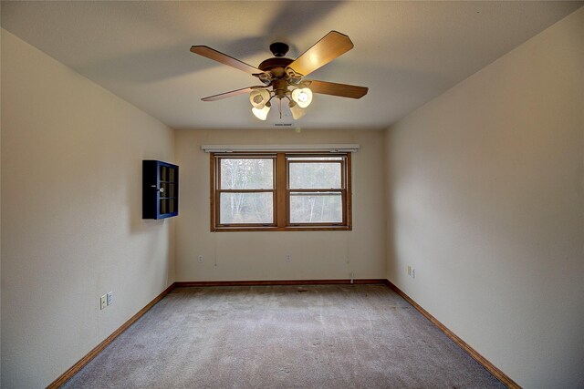carpeted empty room with a ceiling fan and baseboards