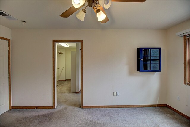spare room featuring carpet, visible vents, a ceiling fan, and baseboards