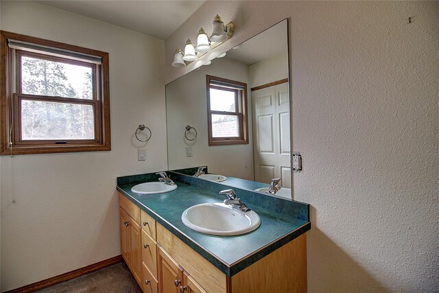 bathroom featuring double vanity, baseboards, and a sink