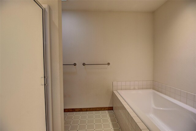 full bathroom with a garden tub and baseboards