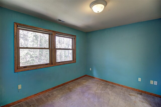 spare room featuring baseboards, carpet floors, and visible vents