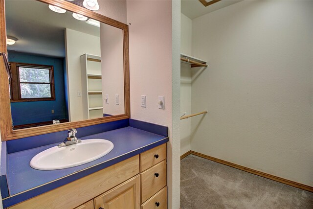 bathroom featuring baseboards, a spacious closet, and vanity
