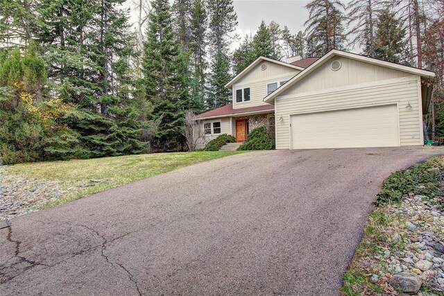 view of front of property featuring a garage, a chimney, a front lawn, and aphalt driveway