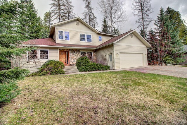 traditional-style house with an attached garage, driveway, stone siding, and a front yard