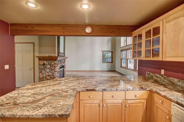 kitchen featuring dishwasher, light brown cabinets, a fireplace, glass insert cabinets, and a textured ceiling