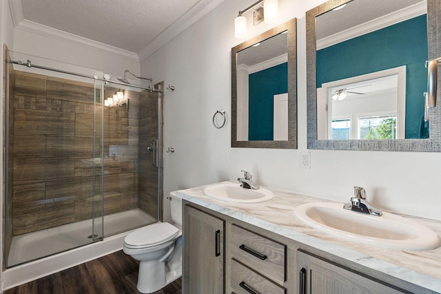 full bathroom with toilet, ornamental molding, a sink, and a stall shower