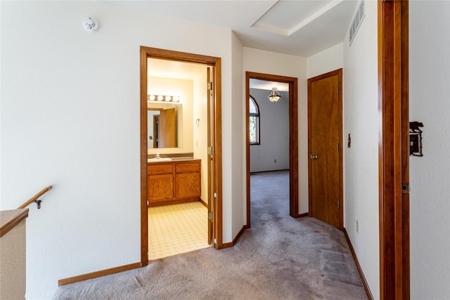 hallway featuring visible vents, a sink, and carpet floors
