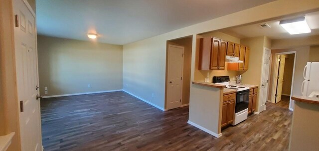 1034 Main St, Corvallis, MT 59828 - kitchen featuring brown cabinets, electric range oven, under cabinet range hood, dark wood-type flooring, and freestanding refrigerator