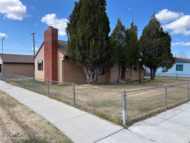 view of front of home with a chimney, roof with shingles, a front yard, and a fenced front yard