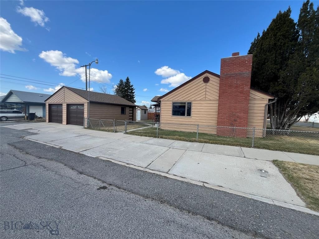 view of home's exterior featuring a garage, a chimney, fence, and an outdoor structure
