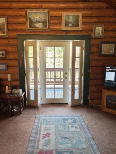 doorway with carpet flooring and log walls