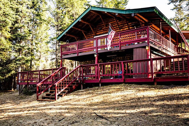 back of property featuring stairs, a wooden deck, and log exterior
