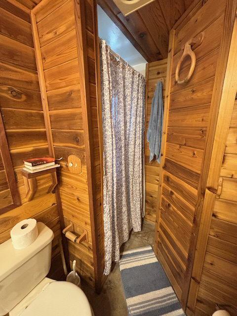 bathroom featuring a shower with curtain, wood walls, and toilet