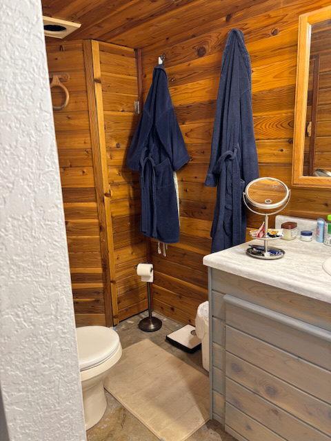 bathroom with wood walls, vanity, wood ceiling, and toilet