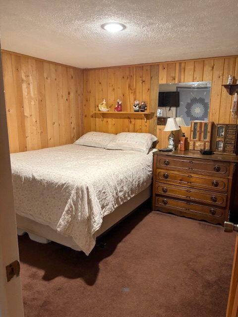 carpeted bedroom with a textured ceiling and wooden walls