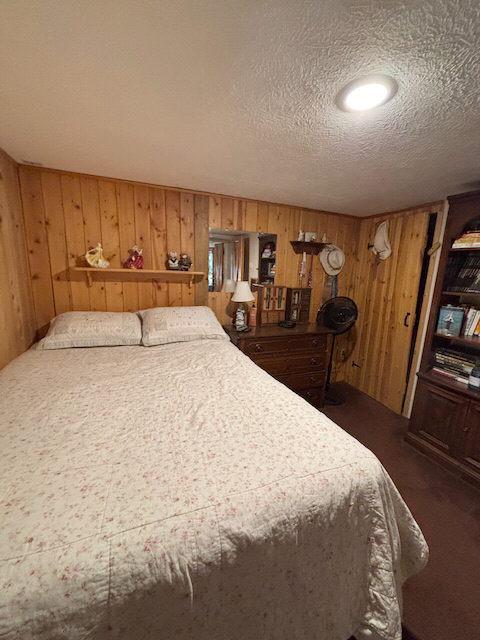carpeted bedroom with wooden walls and a textured ceiling